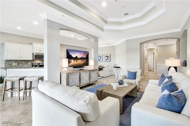 tiled living room featuring ornamental molding and a tray ceiling