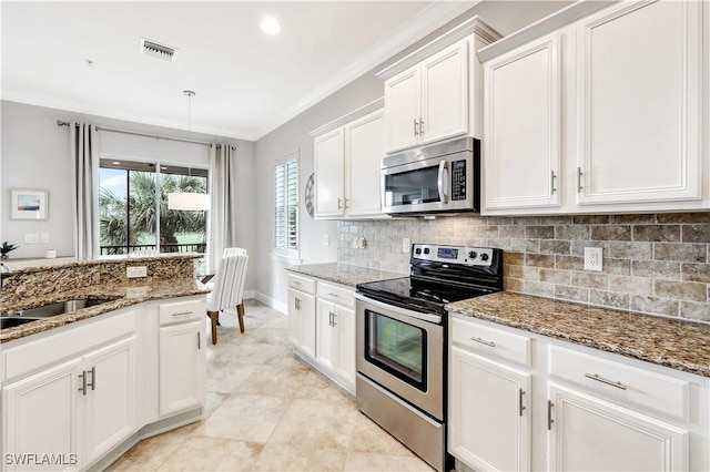 kitchen featuring appliances with stainless steel finishes, white cabinetry, dark stone countertops, decorative backsplash, and ornamental molding