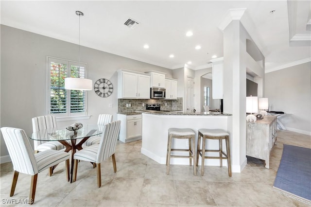 kitchen featuring appliances with stainless steel finishes, tasteful backsplash, white cabinets, kitchen peninsula, and crown molding