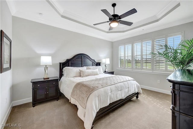 bedroom featuring light carpet, a tray ceiling, and ornamental molding