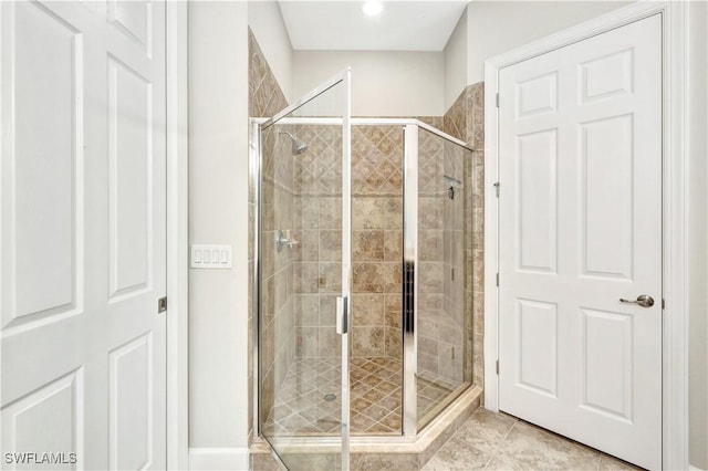 bathroom with a shower with door and tile patterned floors