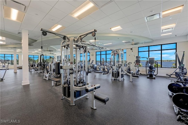 gym with decorative columns, a drop ceiling, and ceiling fan