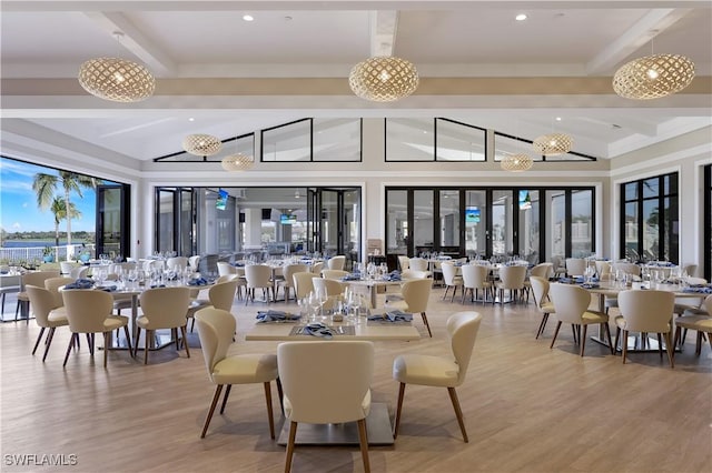 dining area featuring beam ceiling, high vaulted ceiling, and light hardwood / wood-style floors