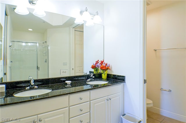 bathroom with tile patterned flooring, vanity, toilet, and a shower with shower door