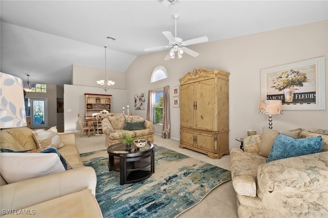 carpeted living room with ceiling fan with notable chandelier and high vaulted ceiling