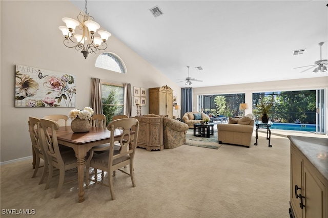 carpeted dining area with ceiling fan with notable chandelier and high vaulted ceiling