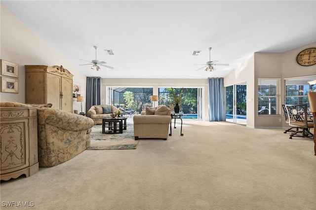 carpeted living room featuring ceiling fan and a high ceiling