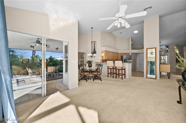 living room with light carpet, a high ceiling, and ceiling fan with notable chandelier