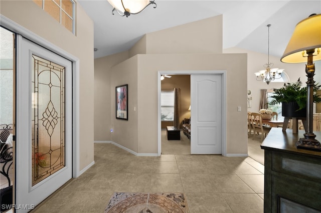 tiled entryway featuring ceiling fan with notable chandelier and vaulted ceiling