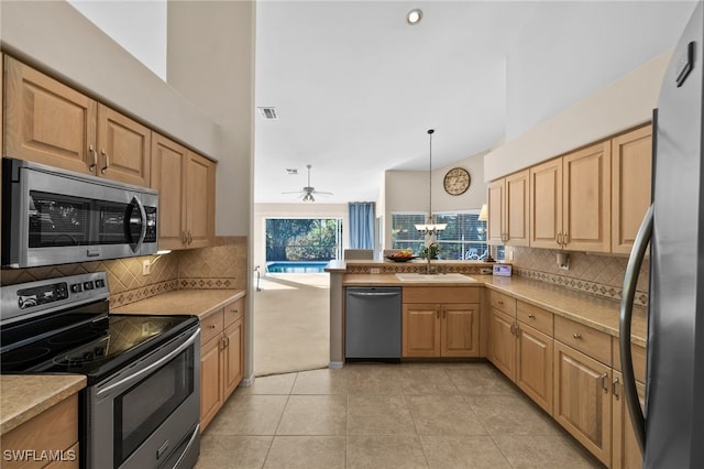 kitchen featuring ceiling fan with notable chandelier, stainless steel appliances, sink, light tile patterned floors, and pendant lighting