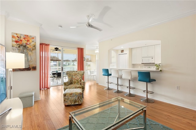 living room featuring ornamental molding, ceiling fan, and light wood-type flooring