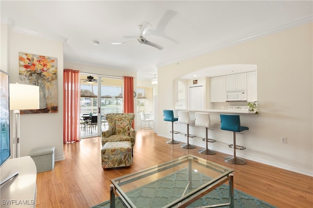 living area featuring a ceiling fan, light wood finished floors, baseboards, and ornamental molding