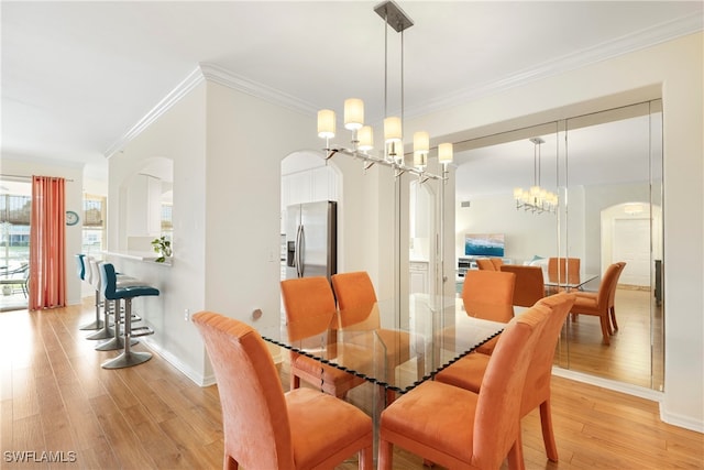 dining area with a notable chandelier, crown molding, and light hardwood / wood-style floors