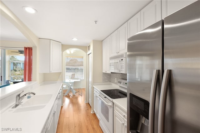 kitchen featuring arched walkways, a sink, white appliances, and plenty of natural light