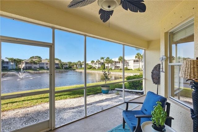 sunroom / solarium featuring a water view, ceiling fan, and a residential view