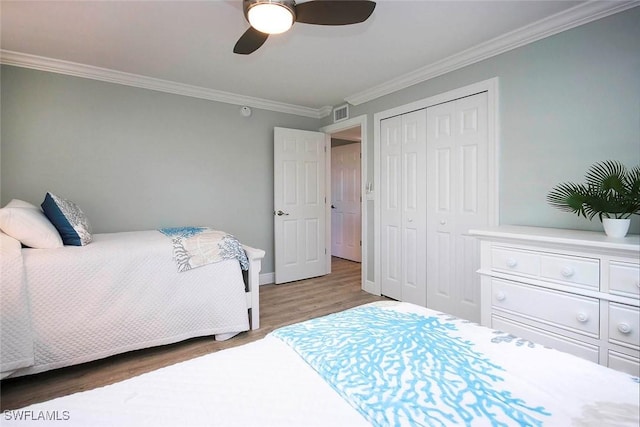 bedroom with ceiling fan, a closet, wood-type flooring, and ornamental molding