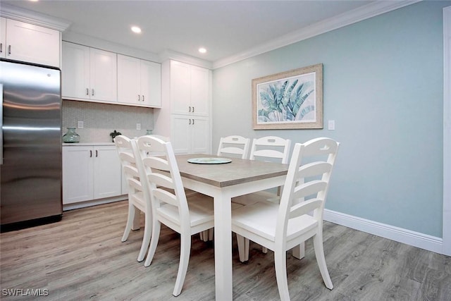 dining space with crown molding and light hardwood / wood-style flooring