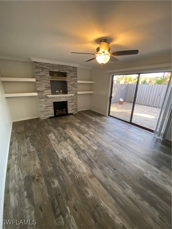 unfurnished living room with dark hardwood / wood-style flooring, ceiling fan, and a large fireplace