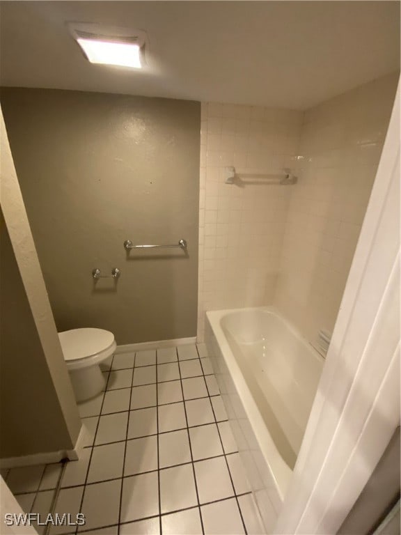 bathroom featuring tile patterned flooring, tiled shower / bath combo, and toilet