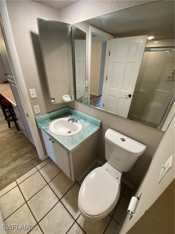 bathroom featuring tile patterned flooring, vanity, a shower with door, and toilet