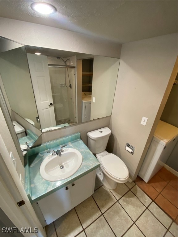 bathroom featuring vanity, tile patterned flooring, toilet, walk in shower, and washer / clothes dryer