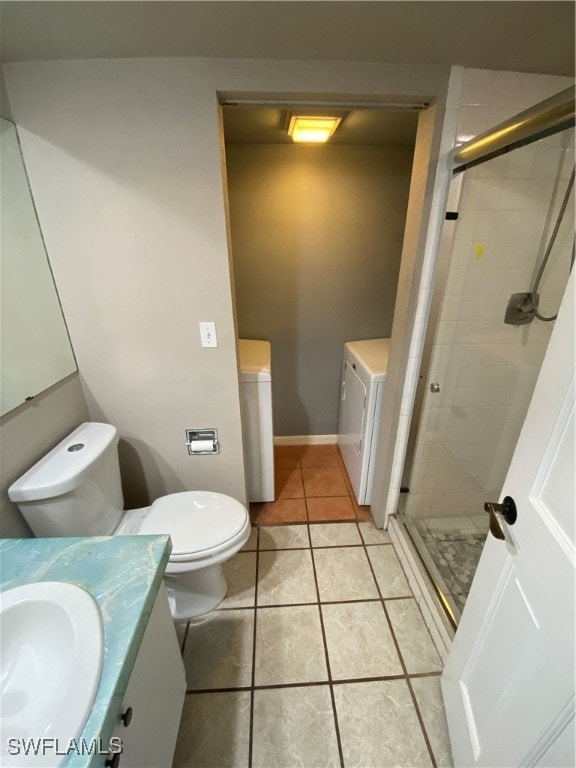 bathroom with separate washer and dryer, tile patterned floors, toilet, a shower with door, and vanity