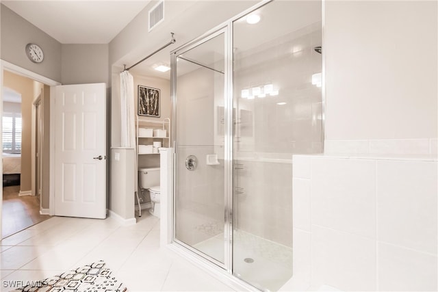 bathroom featuring tile patterned flooring, toilet, and a shower with shower door