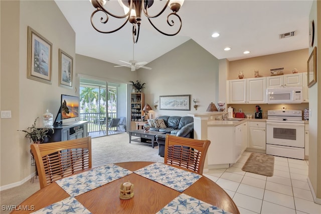 tiled dining space featuring sink, ceiling fan with notable chandelier, and lofted ceiling