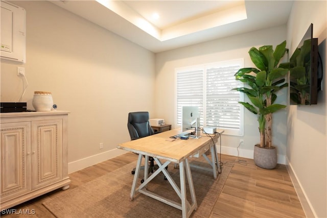 14248 Laguna Springs Ln, Naples, FL 34114 - home office featuring light wood finished floors, baseboards, and a tray ceiling