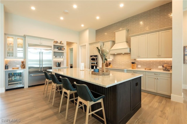 14248 Laguna Springs Ln, Naples, FL 34114 - kitchen featuring wine cooler, appliances with stainless steel finishes, premium range hood, a breakfast bar area, and open shelves