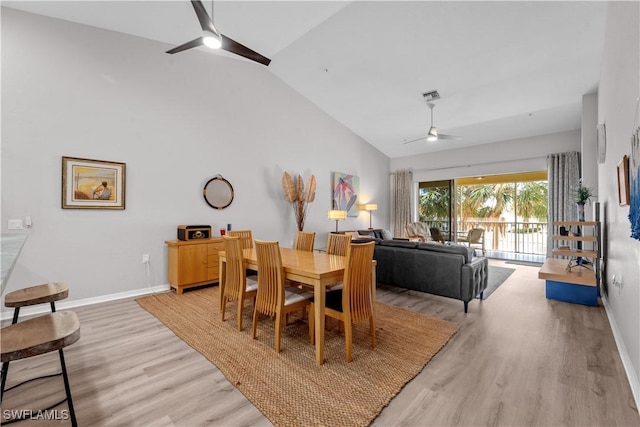 dining room with high vaulted ceiling, light wood-type flooring, a ceiling fan, and baseboards