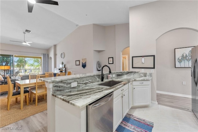 kitchen with stainless steel dishwasher, a ceiling fan, white cabinets, a sink, and light stone countertops