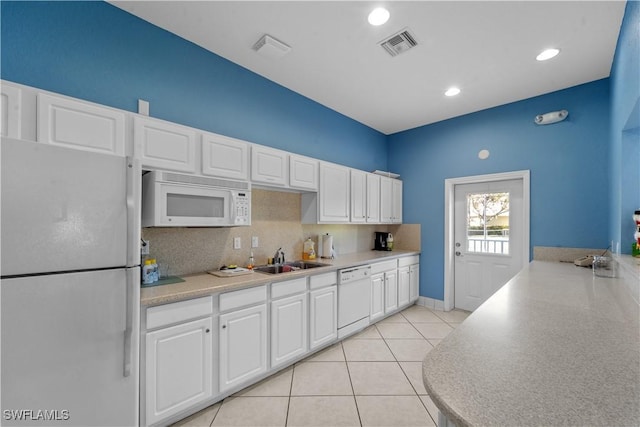 kitchen with light tile patterned floors, visible vents, white cabinetry, a sink, and white appliances