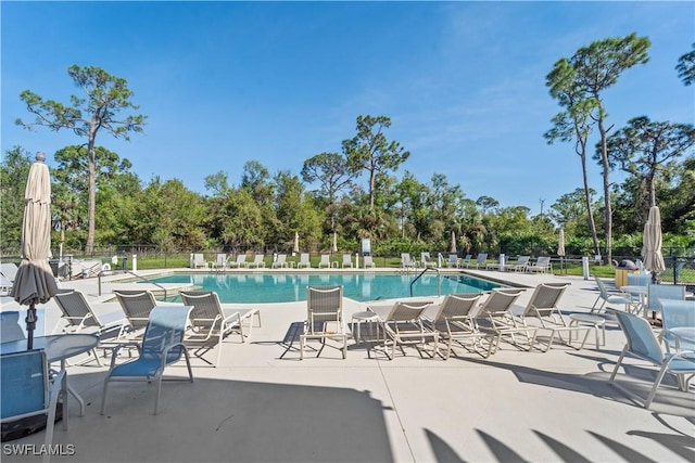 community pool with a patio and fence