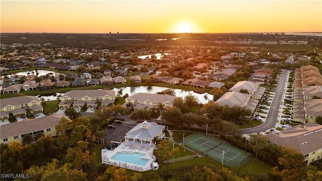 aerial view at dusk featuring a residential view and a water view