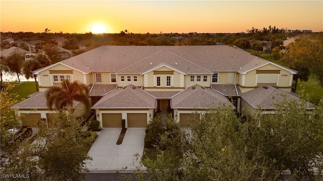 view of front facade featuring an attached garage, a shingled roof, and concrete driveway