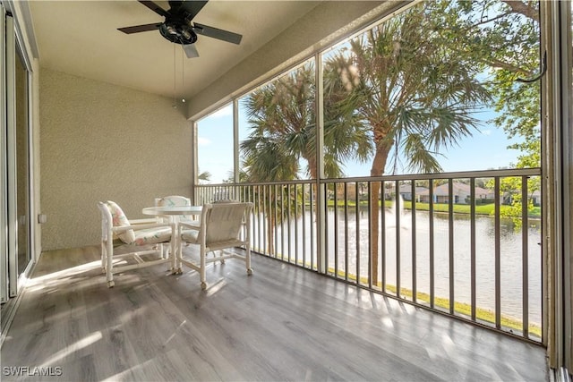 unfurnished sunroom featuring a water view and ceiling fan