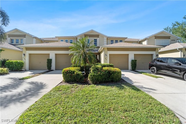 multi unit property featuring a front lawn, concrete driveway, an attached garage, and stucco siding