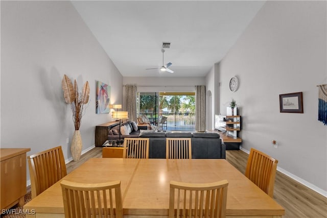 dining area with arched walkways, wood finished floors, visible vents, a ceiling fan, and baseboards