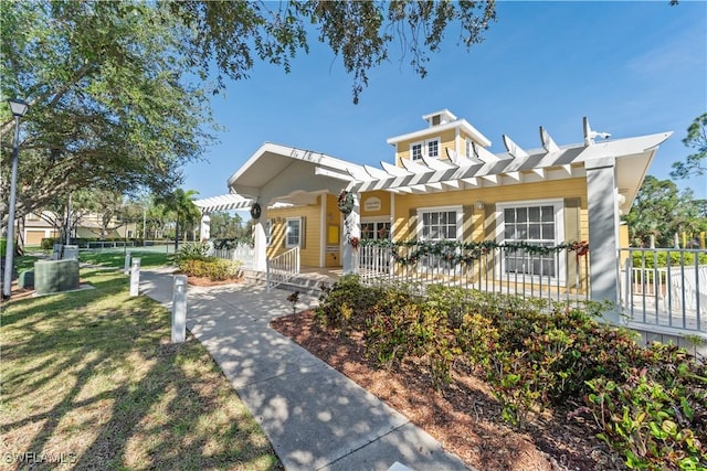 view of front of home featuring covered porch, fence, a pergola, and a front yard