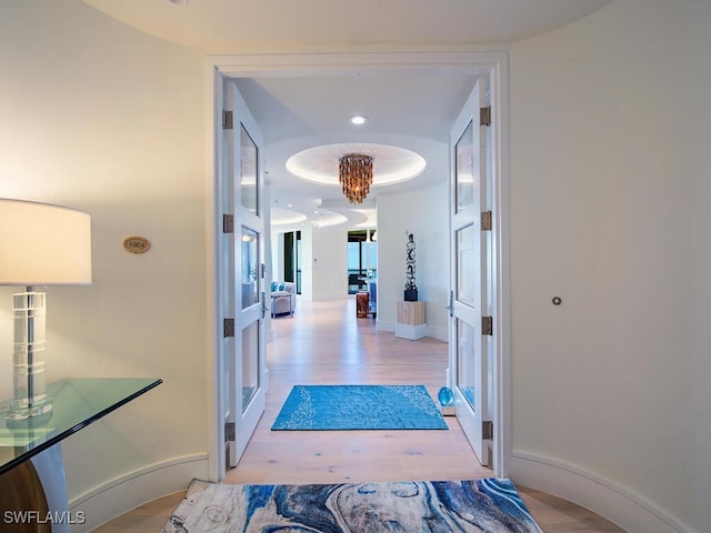 corridor with a chandelier and light wood-type flooring