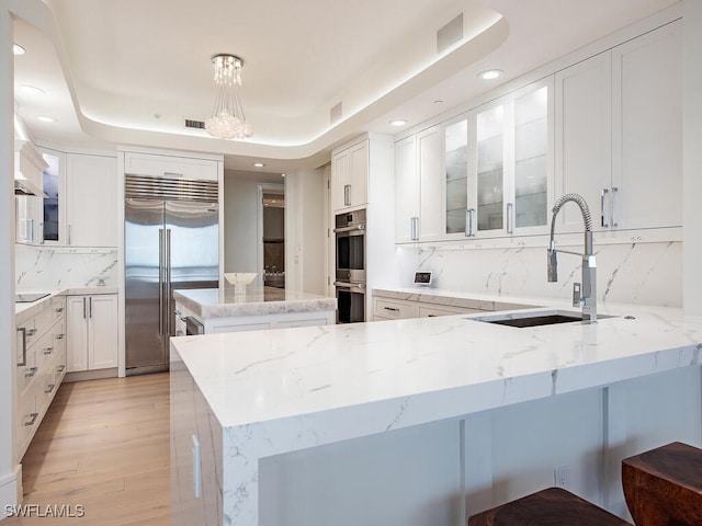 kitchen featuring sink, a raised ceiling, backsplash, white cabinets, and appliances with stainless steel finishes