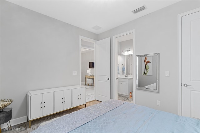 bedroom with connected bathroom and wood-type flooring