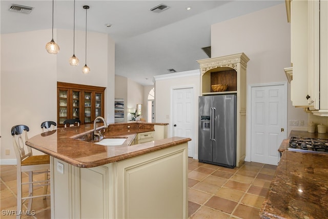 kitchen featuring pendant lighting, a kitchen breakfast bar, sink, cream cabinetry, and high end fridge