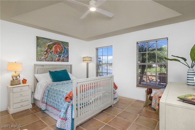 bedroom featuring ceiling fan, a tray ceiling, and multiple windows