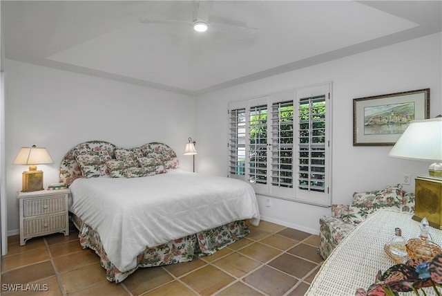 tiled bedroom with a tray ceiling and ceiling fan