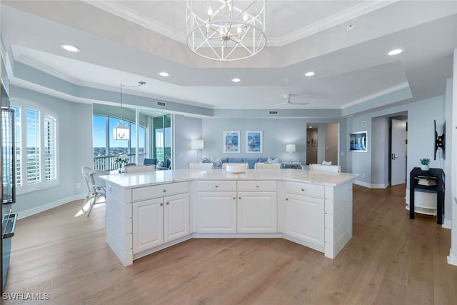 kitchen featuring a raised ceiling, a center island, white cabinets, and light hardwood / wood-style floors