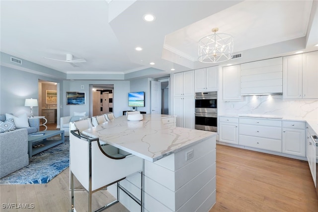 kitchen with a center island, white cabinets, hanging light fixtures, and light hardwood / wood-style floors