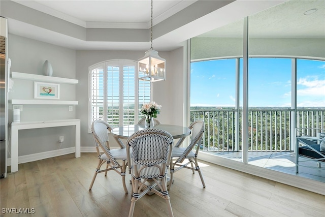 dining room featuring a notable chandelier, a healthy amount of sunlight, crown molding, and light hardwood / wood-style flooring