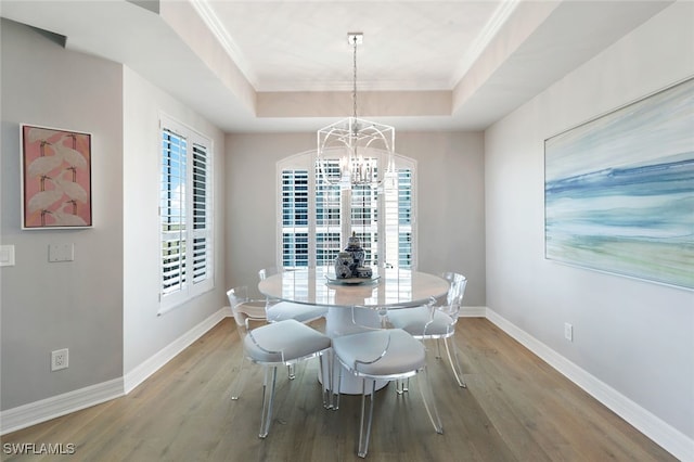 dining room with light wood-type flooring, ornamental molding, and a tray ceiling